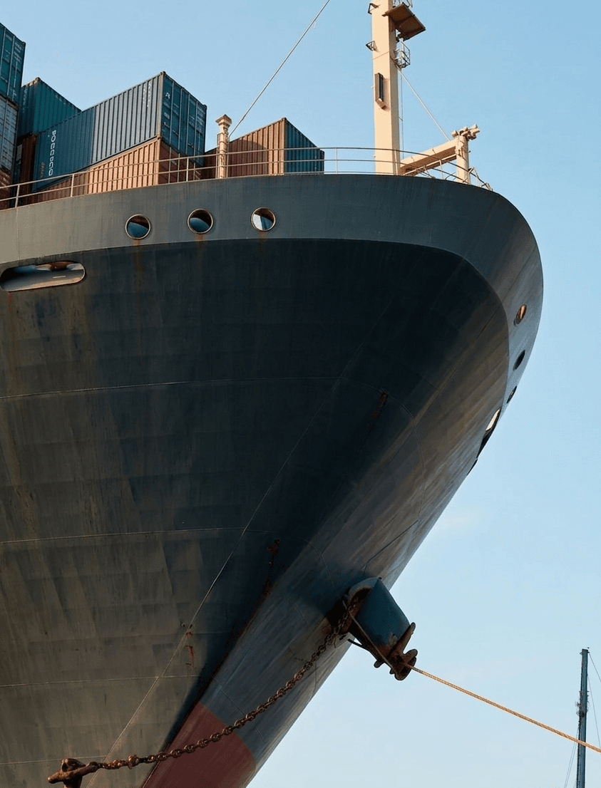 Low-angle view of a container ship's bow rising against the sky