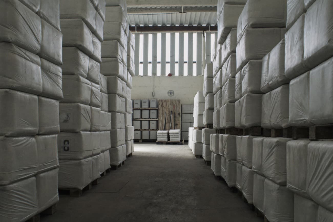 Interior of a warehouse aisle lined with stacked, wrapped pallets